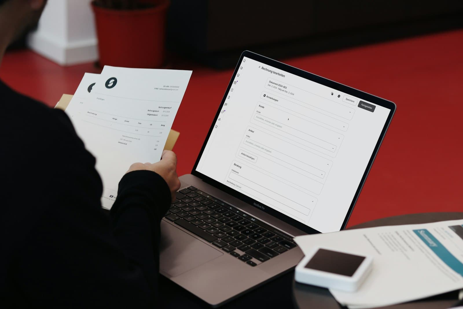 Self-employed business owner reviewing bank statements and invoices at a laptop