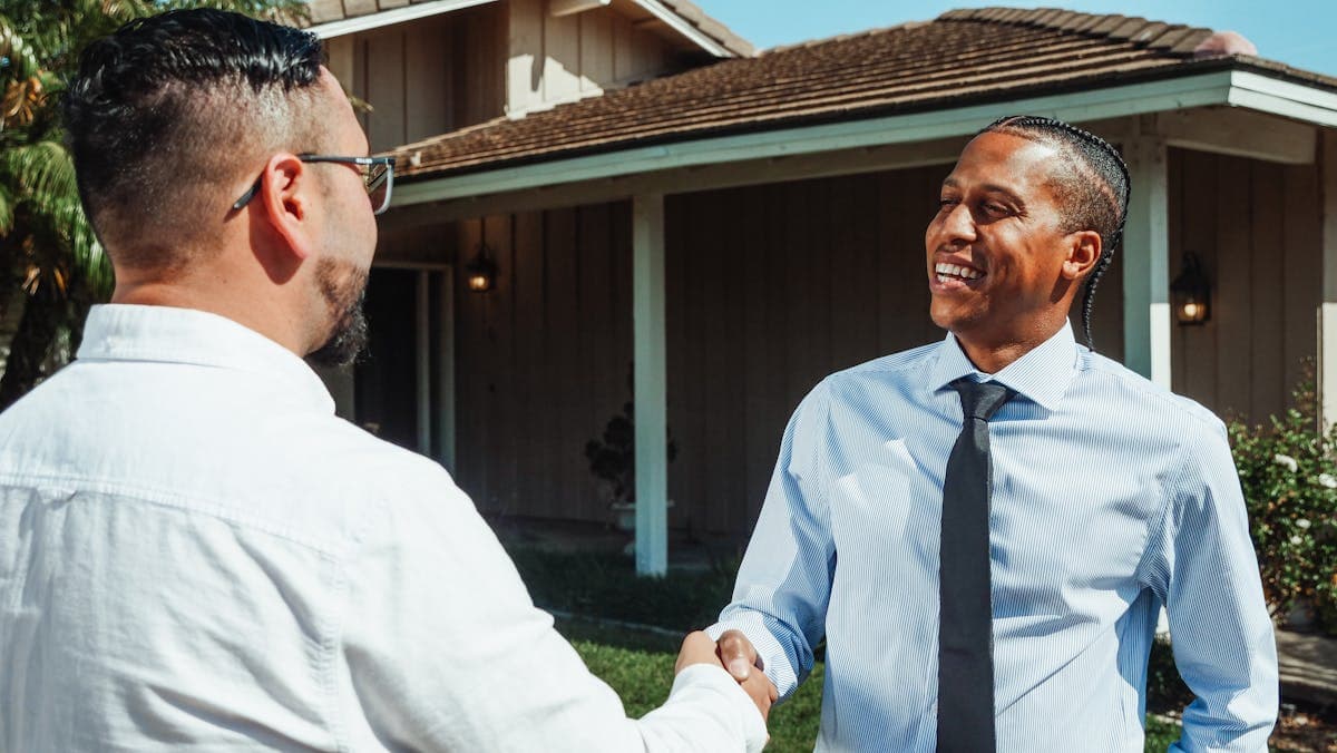 First-time homebuyer meeting with agent in front of house